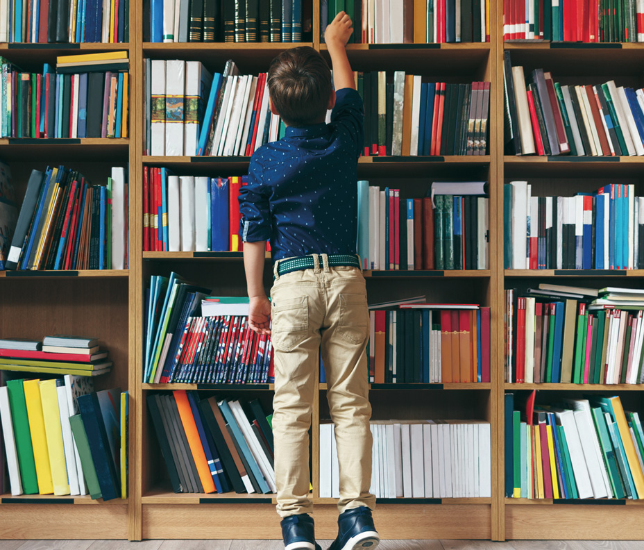 Foto di un ragazzino di spalle che prende un libro da uno scaffale